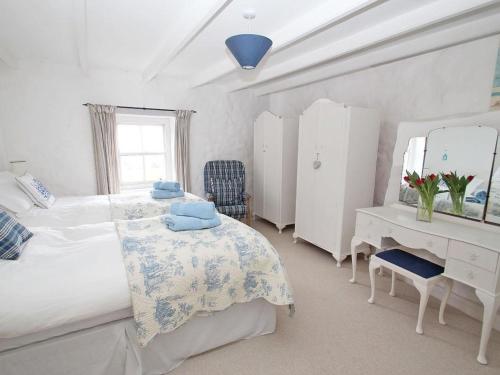 a bedroom with two beds and a desk and a mirror at Woodpecker Cottage in Helston