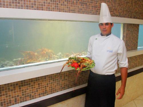 a chef standing in a kitchen holding a bouquet of flowers at Serrambi Resort in Porto De Galinhas