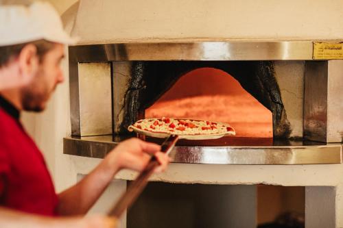 a man taking a pizza out of an oven at Historic Hotel Albrici in Poschiavo