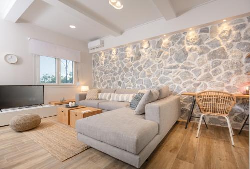 a living room with a couch and a stone wall at Rapanos Apartments in Paleokastritsa