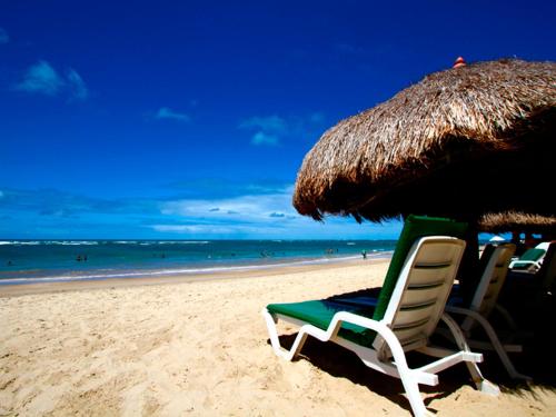 a group of chairs and an umbrella on the beach at Serrambi Resort in Porto De Galinhas