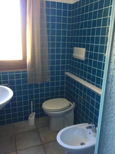 a blue tiled bathroom with a toilet and a sink at Villino Saccu in Costa Paradiso
