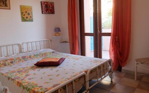 a bedroom with a bed and a window with a door at Villino Saccu in Costa Paradiso