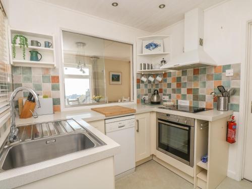 a kitchen with white cabinets and a sink at Wootton Gray in Mousehole