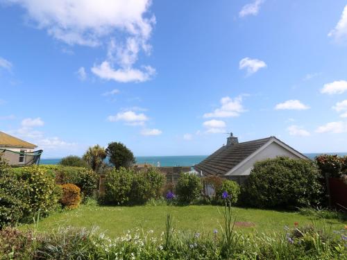 a house with a garden and the ocean in the background at Wootton Gray in Mousehole