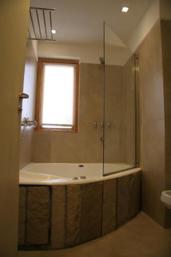 a bathroom with a tub and a shower with a window at Galileo Boutique Hotel in San Carlos de Bariloche