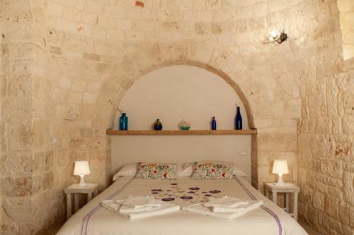 a bedroom with a bed in a stone wall at Le Dieci Porte in Alberobello
