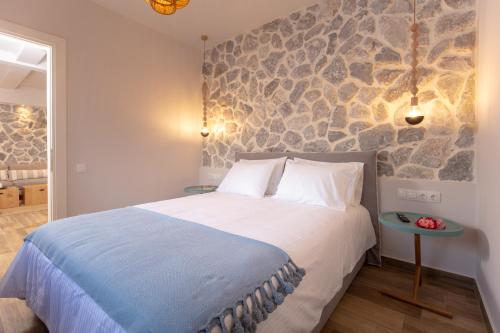 a bedroom with a large bed and a stone wall at Rapanos Apartments in Paleokastritsa