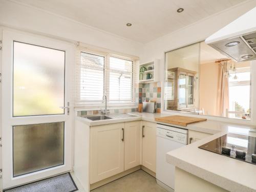 a kitchen with white cabinets and a sink and windows at Wootton Gray in Mousehole