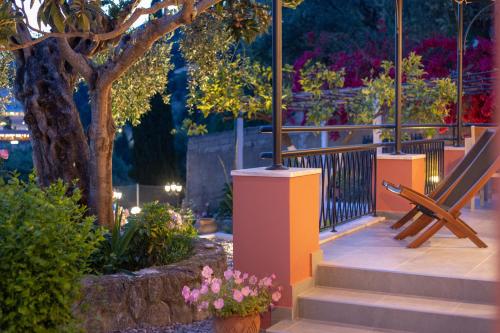 a wooden bench sitting on a porch with flowers at Rapanos Apartments in Paleokastritsa