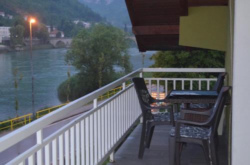 two chairs and a table on a balcony overlooking a river at Apartments Sokolović in Višegrad