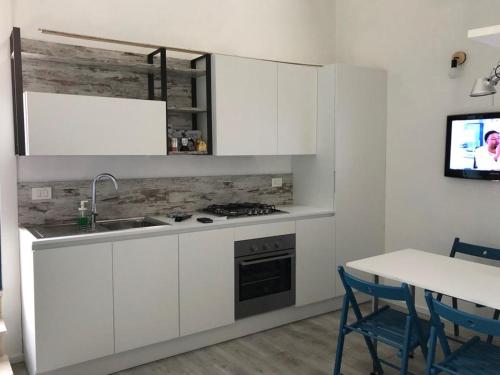 a kitchen with white cabinets and a sink and a table at La casetta di Portopalo in Portopalo