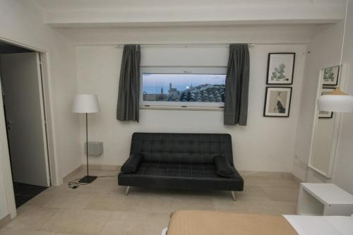 a living room with a black couch and a window at Palazzo di Fazio Suites in San Severo