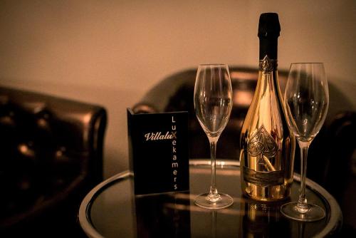 a bottle of champagne and two wine glasses on a table at VillaluX in Kortessem