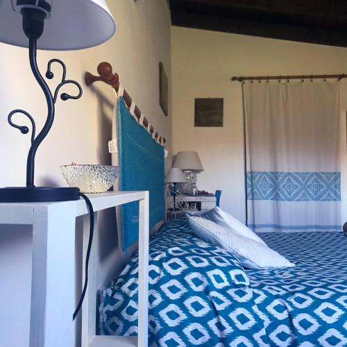 a bedroom with a blue and white bed and a lamp at B&B La Tasgia in Aggius