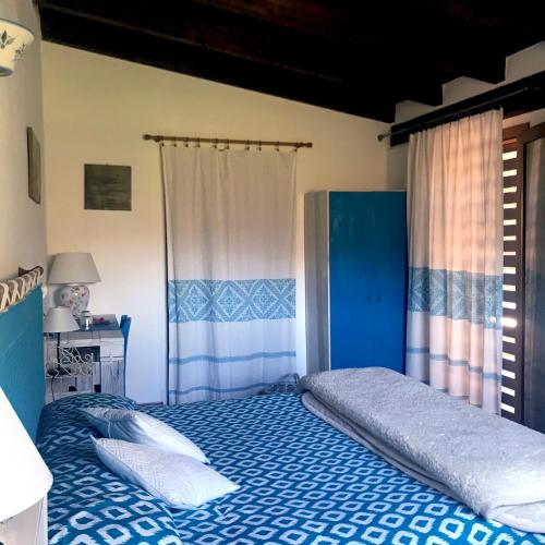 a bedroom with a bed with blue sheets and white pillows at B&B La Tasgia in Aggius