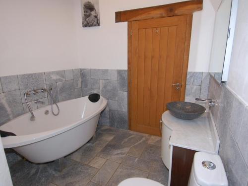 a bathroom with a tub and a toilet and a sink at Hideaway in Tintagel