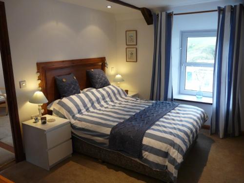 a bedroom with a bed with a blue and white striped blanket at The Keep Pot in Port Isaac