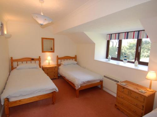 two beds in a room with two windows at Pine Cottage in Falmouth