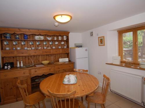 eine Küche mit einem Holztisch mit Stühlen und einem Kühlschrank in der Unterkunft The Old Cider Barn in Wells