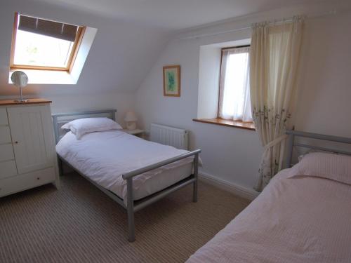 1 dormitorio con 2 camas y ventana en The Old Cider Barn en Wells