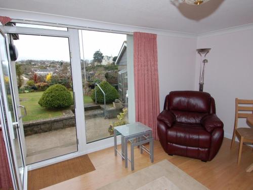 a living room with a chair and a large window at Garden View in Kingskerswell