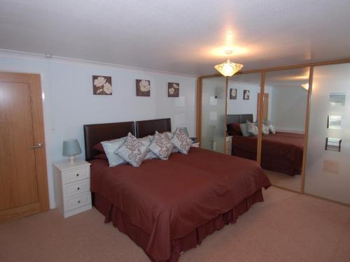 a bedroom with a large bed and a mirror at Garden View in Kingskerswell