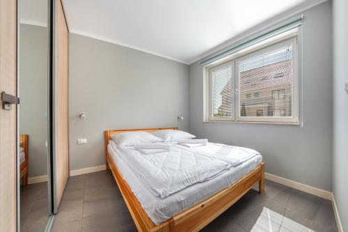 a small bedroom with a bed and a window at Osiedle Wybrzeże, Sun & Snow in Ustronie Morskie