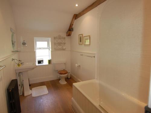 a bathroom with a tub and a toilet and a sink at Quist Cottage in Taunton