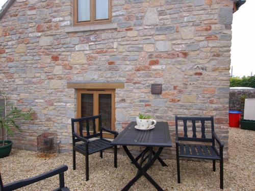 une table et deux chaises devant un bâtiment en pierre dans l'établissement The Old Cider Barn, à Wells