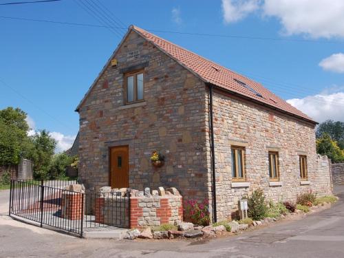 a brick house with a fence in front of it at The Old Cider Barn in Wells