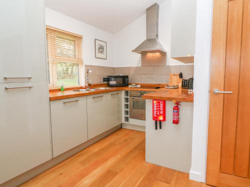 a kitchen with white cabinets and a wooden floor at 1 Lake View in Looe