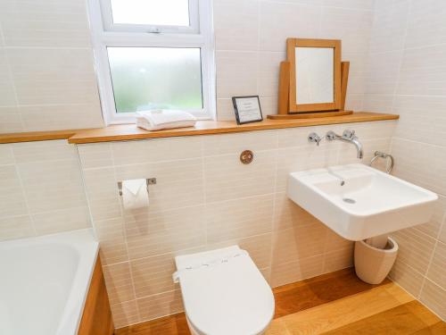 a bathroom with a sink and a toilet and a window at 1 Lake View in Looe