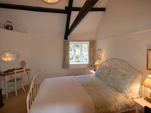 een slaapkamer met een bed, een bureau en een raam bij Quist Cottage in Taunton