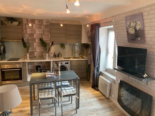 une cuisine avec une table à manger et une cheminée dans l'établissement Les Appartements Le Saint Pierre Barcelonnette, à Barcelonnette