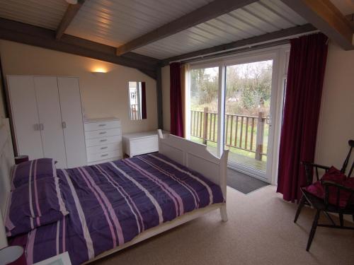 a bedroom with a bed and a large window at Brookfield Lodge in Burstock
