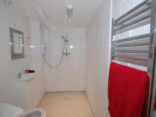 a white bathroom with a shower and a red towel at Brookfield Lodge in Burstock