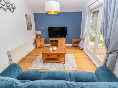 a living room with a blue couch and a tv at 1 Lake View in Looe
