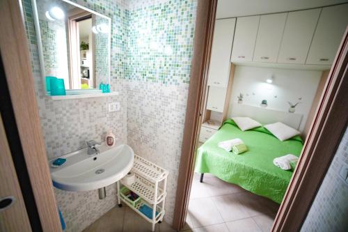 niewielka łazienka z zielonym łóżkiem i umywalką w obiekcie Dolly Monolocali w mieście Porto Cesareo