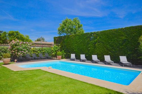 - une piscine dans une cour avec des chaises et une haie dans l'établissement Ferme St Roch, à Robion