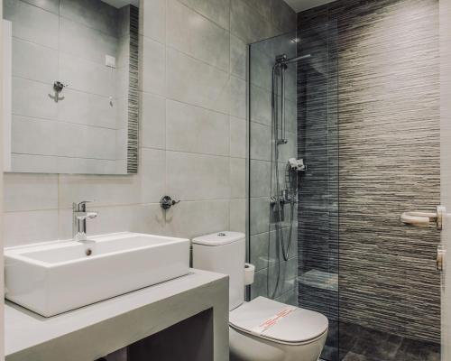 a bathroom with a sink and a toilet and a shower at Poseidonio Hotel in Tinos Town