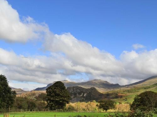 a green field with mountains in the background at Brynkir Tower in Llanfihangel-y-pennant
