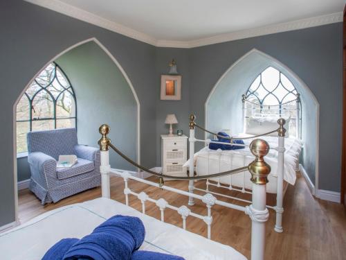 a bedroom with a bed and two arched windows at Brynkir Tower in Llanfihangel-y-pennant
