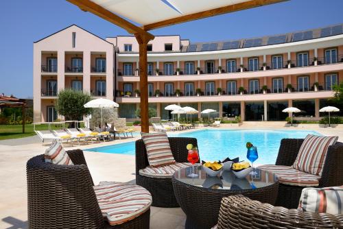 a hotel with a swimming pool and chairs and a table at Hotel Isola Sacra Rome Airport in Fiumicino