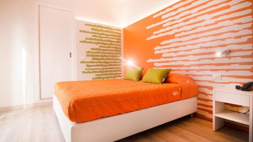 a bedroom with a bed with an orange and white wall at All'Orologio - Boutique Hotel in Caorle