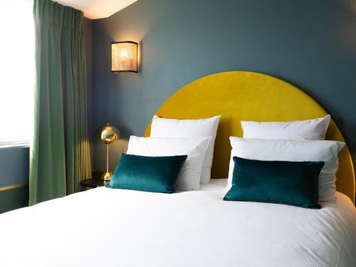 a bedroom with a large bed with blue and white pillows at Hotel Mercure Roscoff Bord De Mer in Roscoff