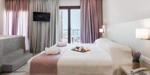 a hotel room with a bed with a tray of food on it at Poseidonio Hotel in Tinos Town