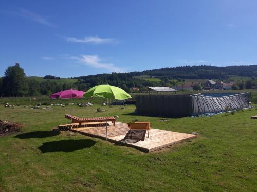 two benches and two umbrellas on a wooden deck at chalets les 5 loups in Gerbépal