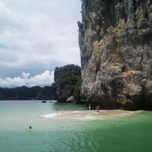 a group of people on a beach near a mountain at Cat Ba Bay Cruises in Cat Ba