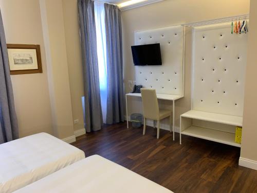 a hotel room with a desk and a tv on a wall at 7 Bell's House in Civitavecchia